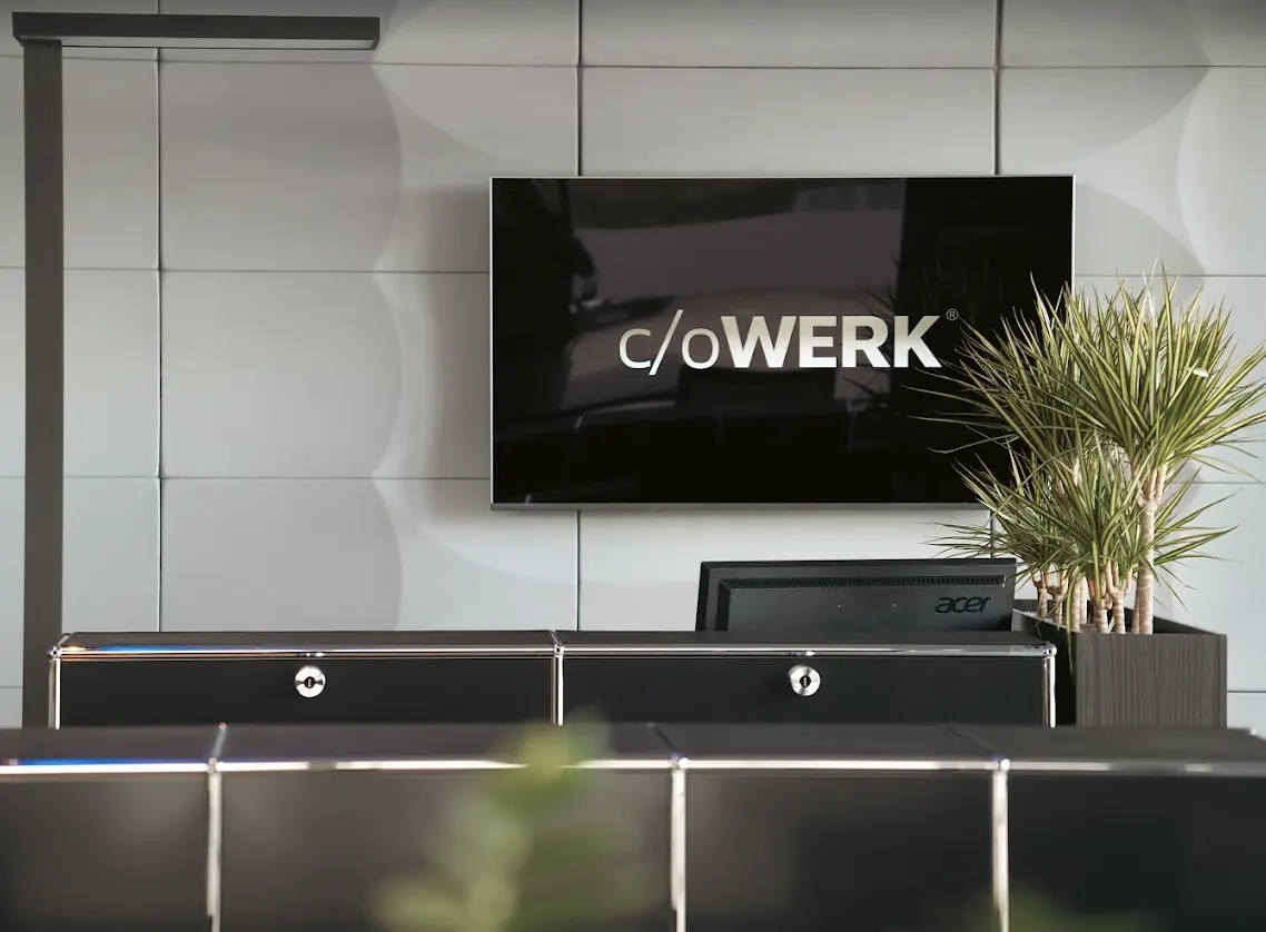 Empfang im c/oWERK mit Bildschirm, Logo und Pflanze